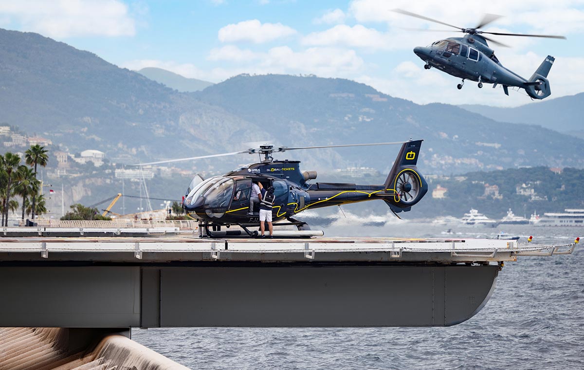 Helicopter landing on a coastal helipad with mountains behind